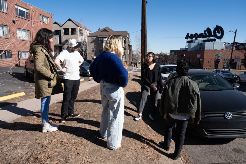 A group of people thoughtfully observing vehicular damage.