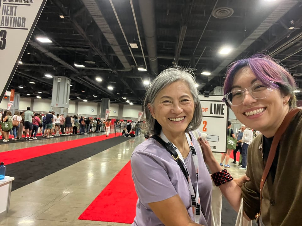 Photo of Gale Galligan with their mom. They're smiling by a signing line at the National Book Festival.