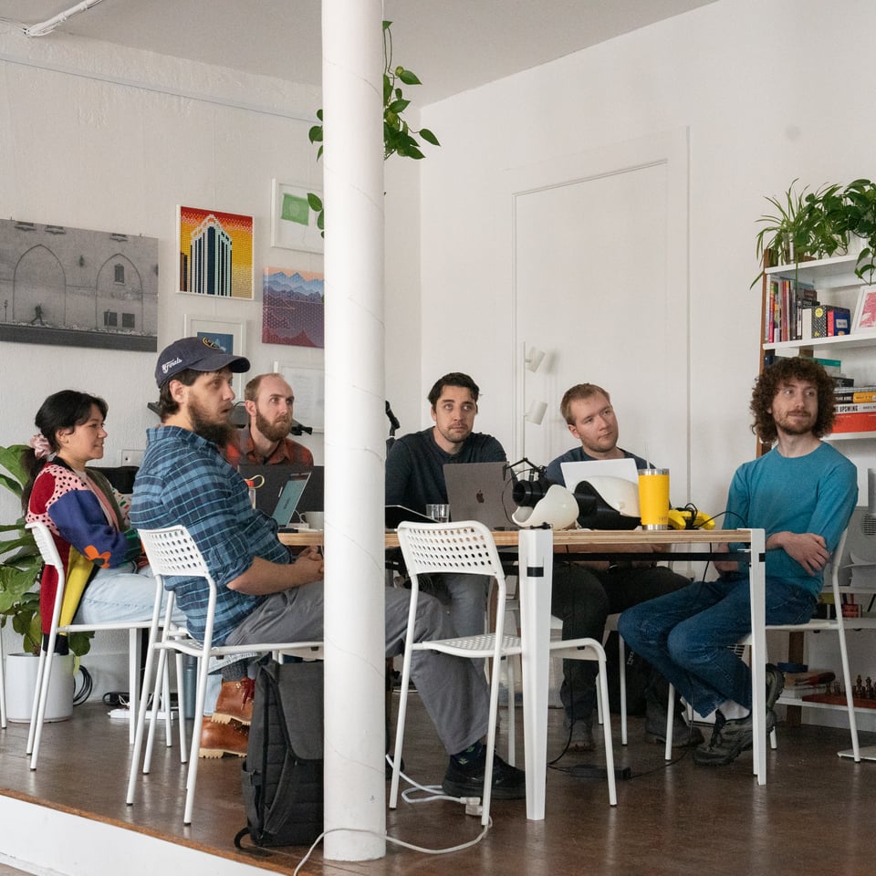 A group around a table looking toward a TV, just out of frame.