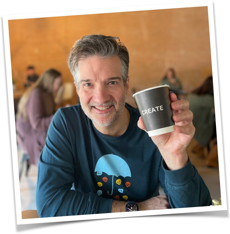 Photo of Stephen smiling, and holding a coffee cup that says "Create"