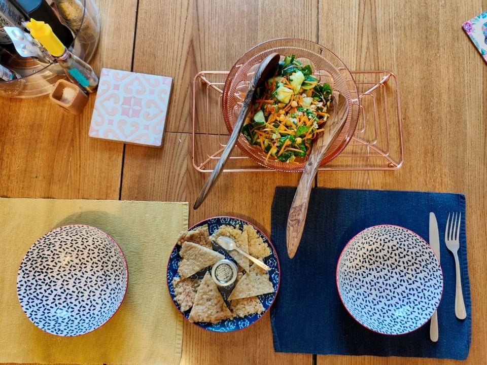 A table set with bowls, a salad and a plate of pancake triangles