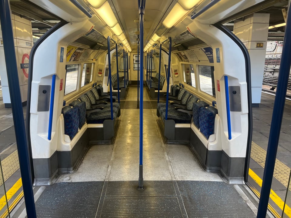 A view down the middle of a Tube carriage in which all the seats are empty.