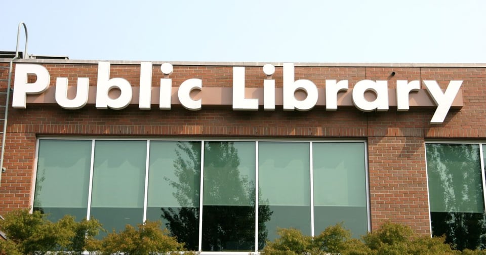 Stock image of a sign on the outside of a library. It says "Public Library" in white.