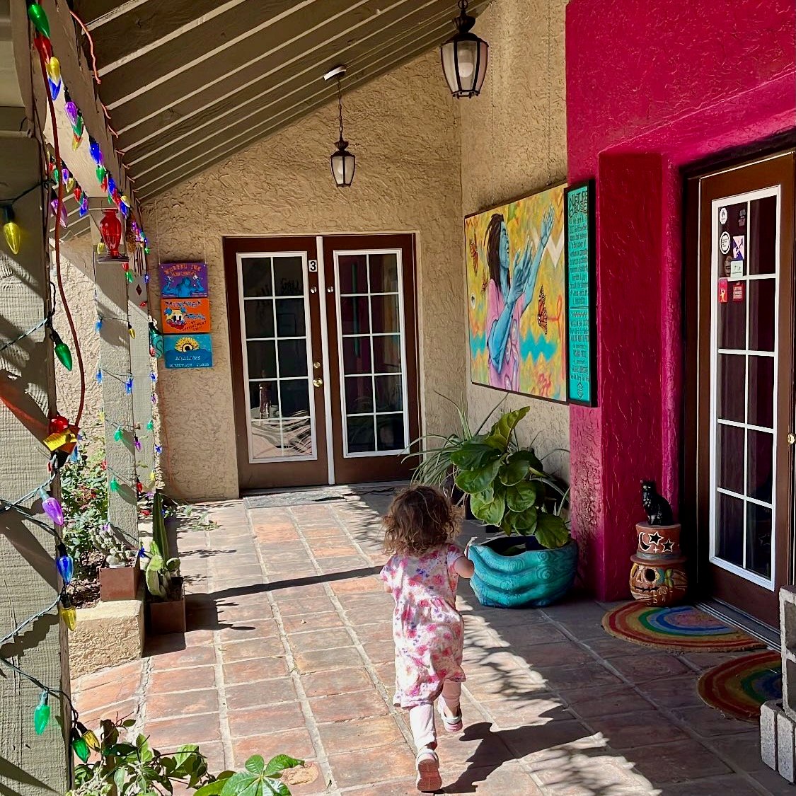 The entrance to Nurture House: tile floor, French doors, colorful paintings, and my daughter running to go inside.