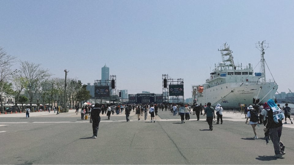 2026年大港開唱南霸天舞台,12:30開演的演出,外面在幾個小時前就排起了長長的隊伍。照片中進場後人群走向舞,離舞台大概還有兩、三百公尺的距離,旁邊停泊的是台大的海研船。