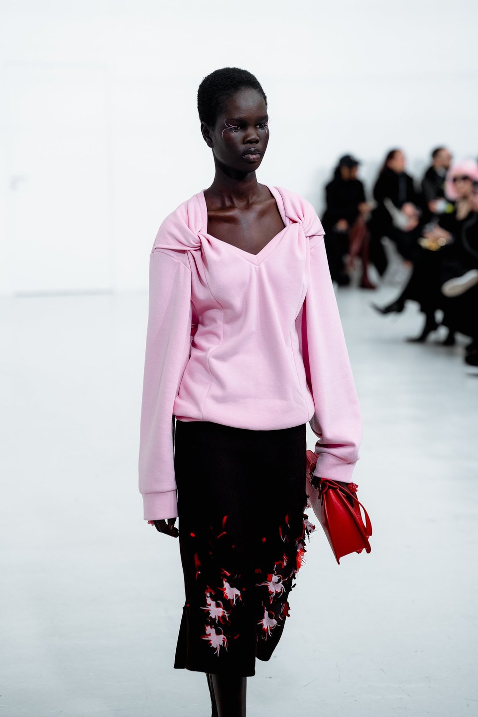 A model walking down the runway with a skirth with slash marks going through it