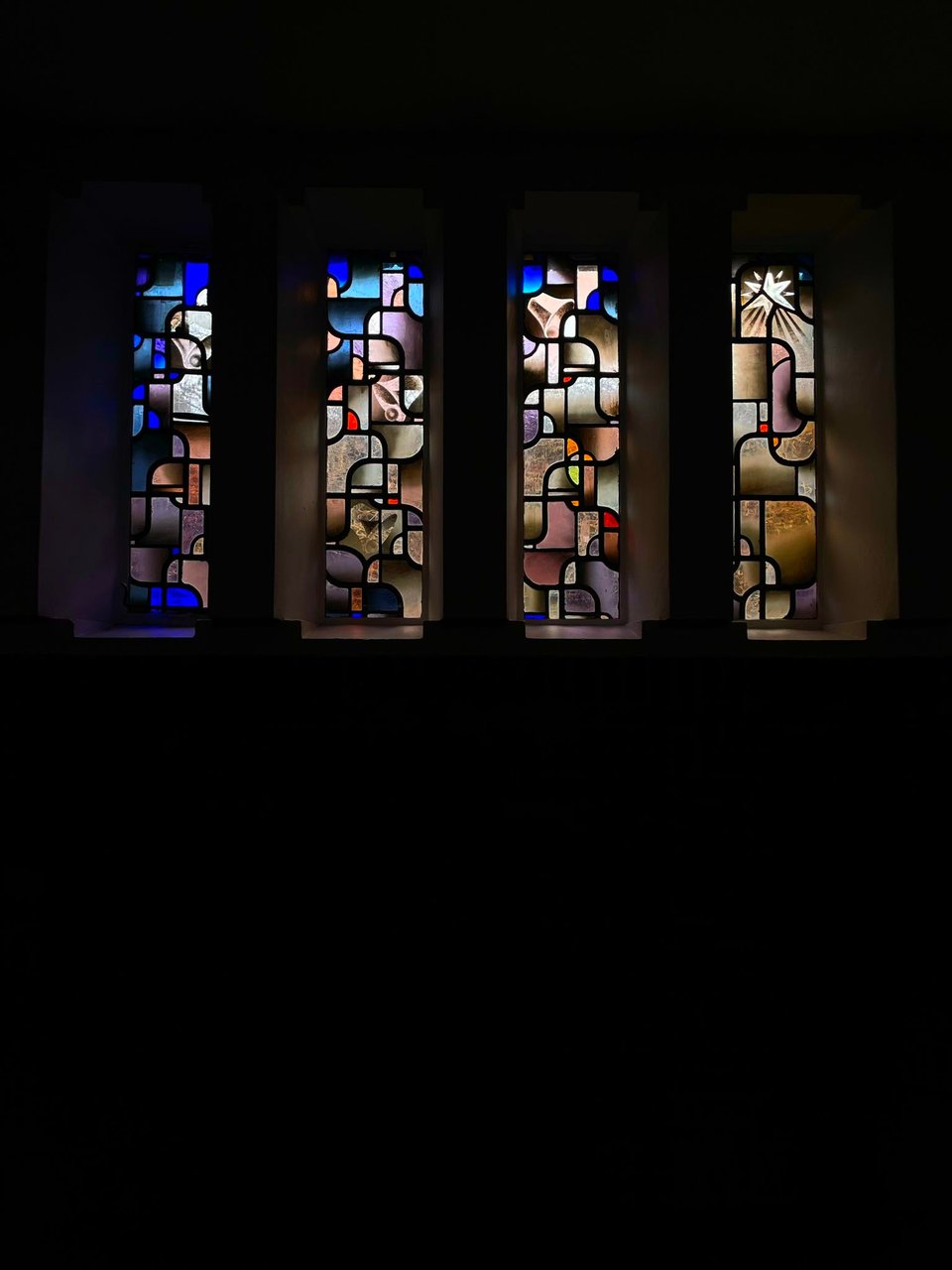 Four colorful stained glass windows. They are colorful, and have no particular subject.