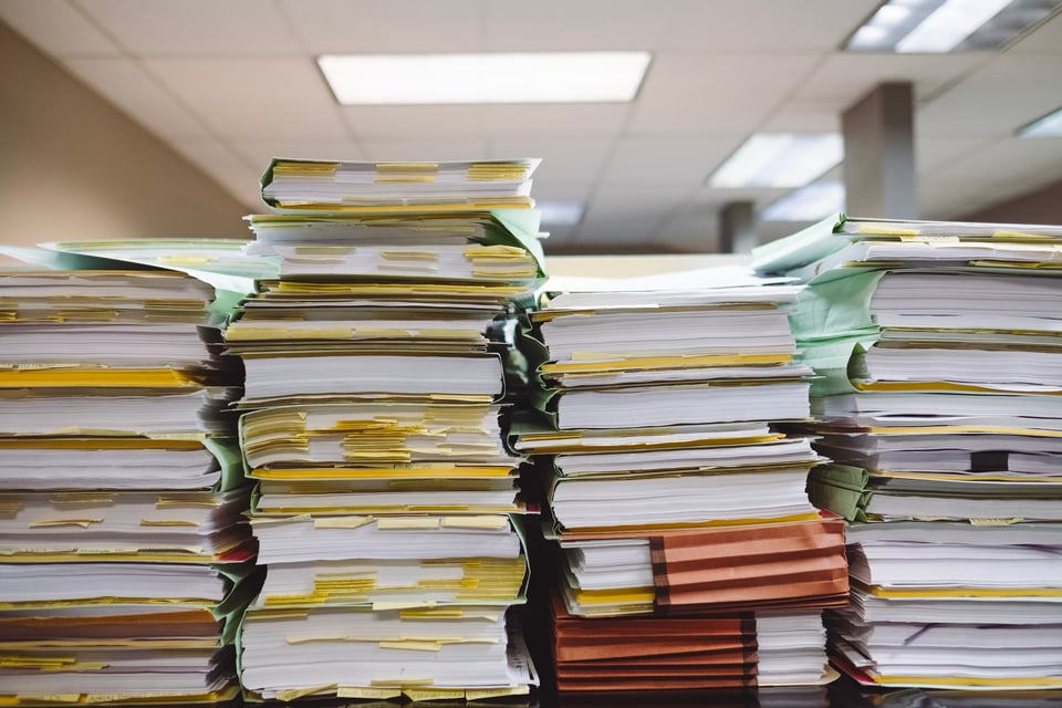 A photo of lots of file folders stacked and disorganized.