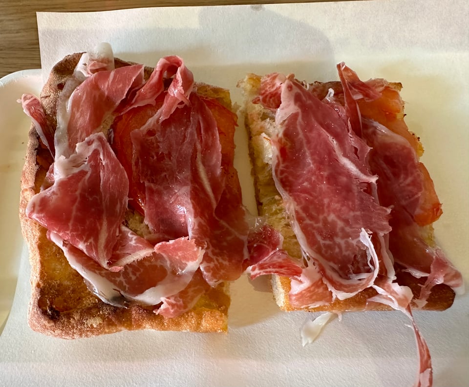 photo of coca jamon, a flatbread with sliced pork, tomatoes & oil