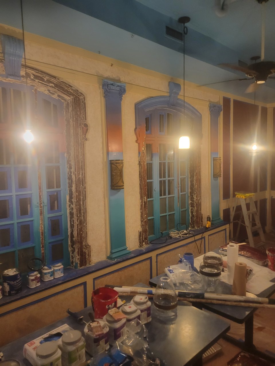 The windows of the bar, half scraped, with plenty of blue and orange paint depicting a sunset.