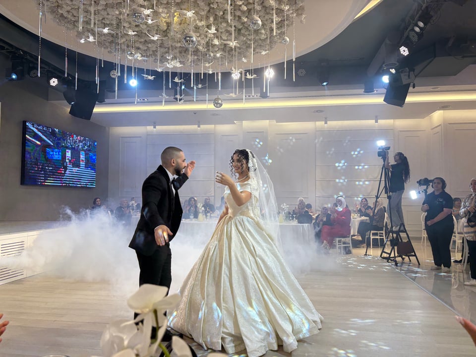 The bride and groom dancing on the dance floor with lights, smoke, and photographers