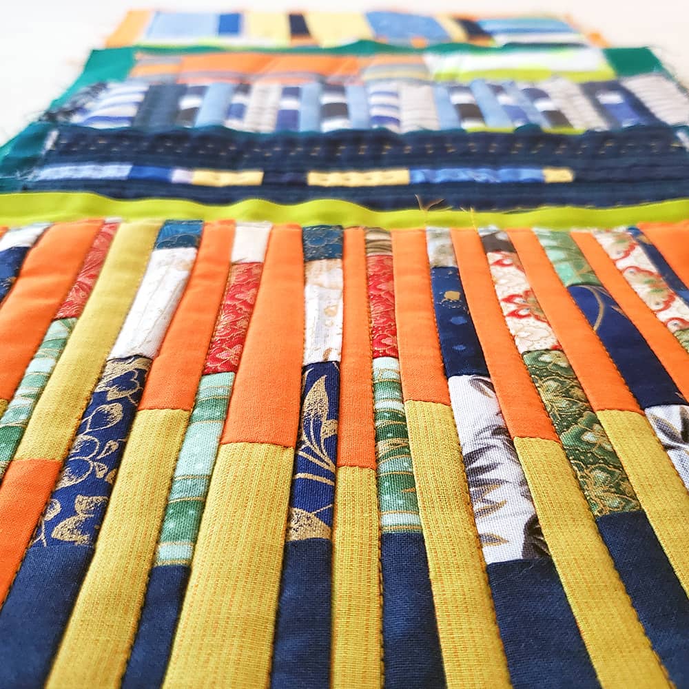 Photo of 5 small patchwork quilts arranged in a row. The image is from a very clos perspective, creating a blurred background.