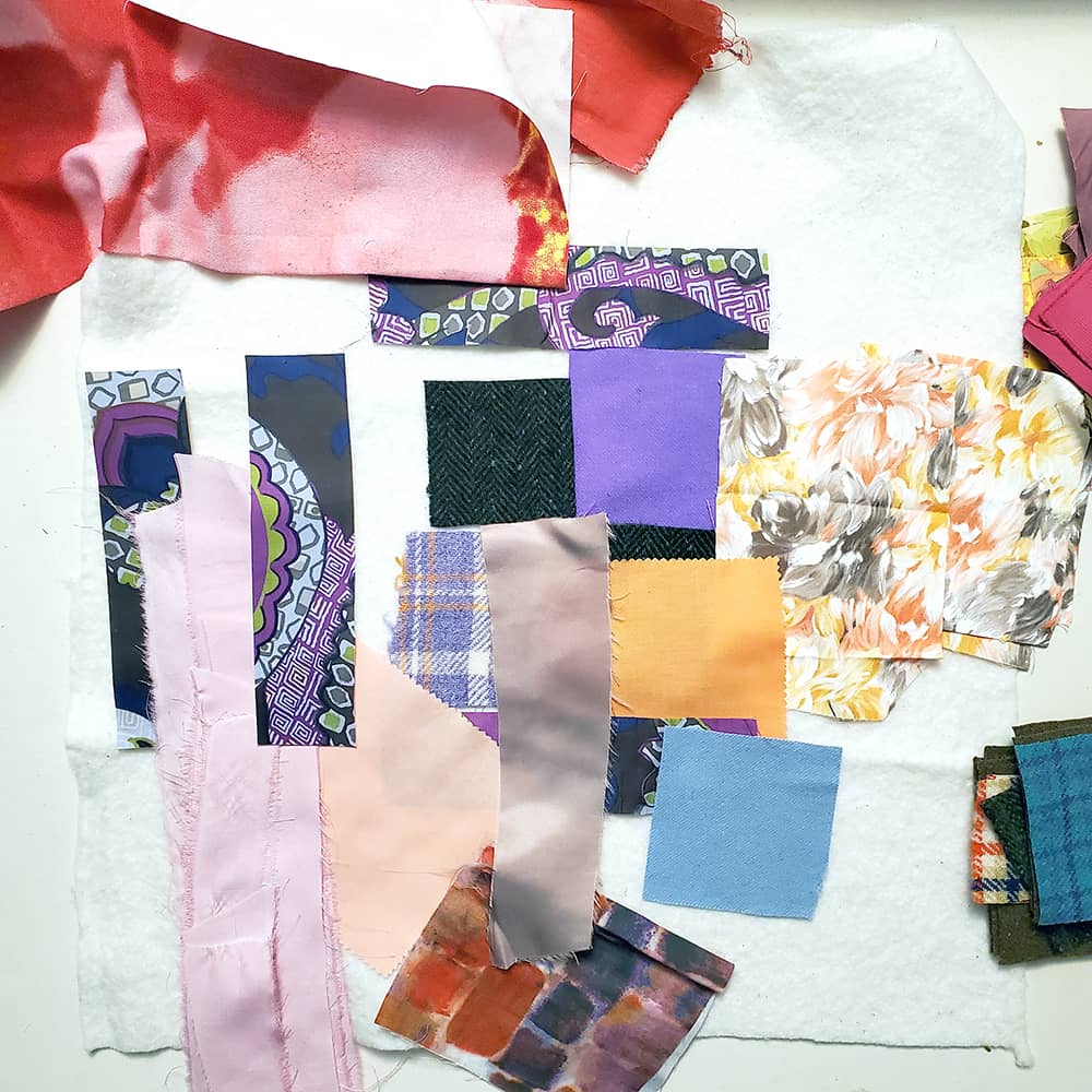 Photo of fabric scraps in various colors placed on a white piece of quilt batting.