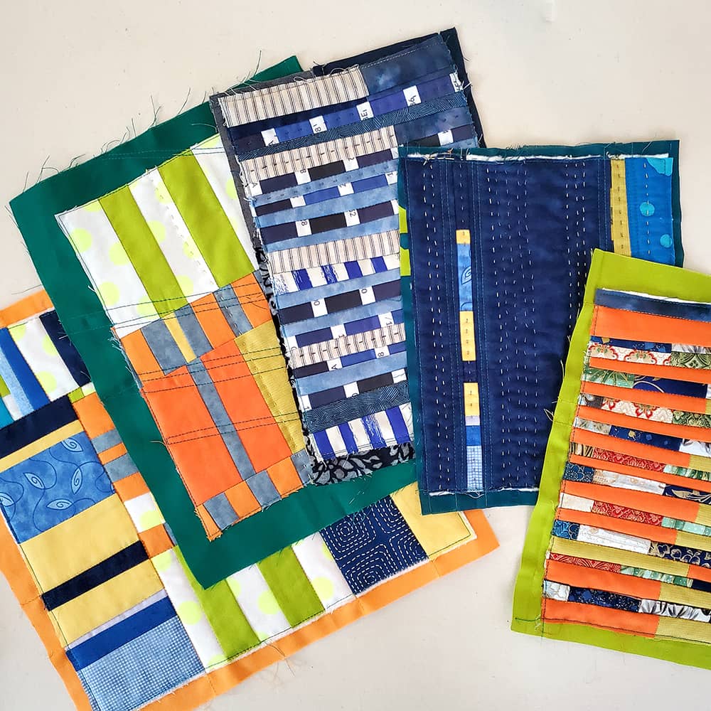 Photo of 5 small patchwork quilts arranged in an arc against a light background.